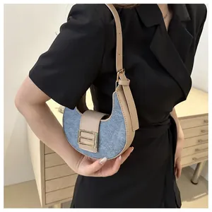 Detalle del bolso vaquero de media luna con ribete de cuero caqui y hebilla dorada