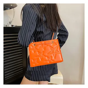 Détail macro du sac orange vif avec matelassage en étoile et bandoulière en chaîne