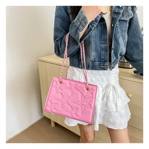 Gros plan d'un sac rose avec étoiles embossées 3D et bandoulière chaîne dorée