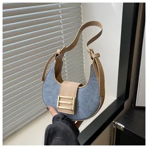 Detalle del bolso hobo con tela vaquera azul, cuero caqui y hebilla de metal dorado