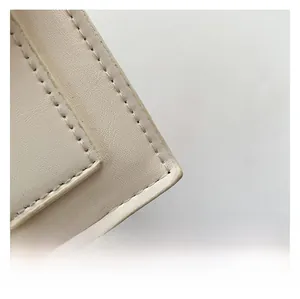 Macro detail of creamy white leather handbag showing fine stitching and litchi texture