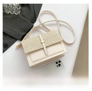 Detail view of cream crossbody bag featuring a woven flap and elegant gold round lock clasp