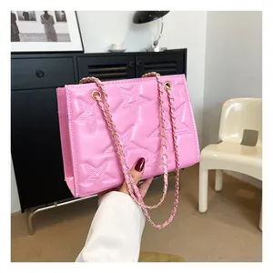 Gros plan du sac à bandoulière rose avec motifs d'étoiles gaufrés et chaîne dorée