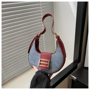 Detalle de bolso medialuna en patchwork de cuero rojo y tela gris con hebilla oro