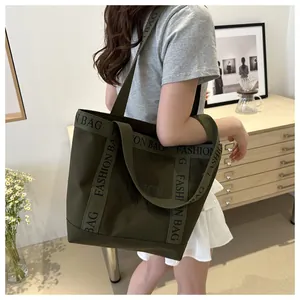 Détail du sac fourre-tout en toile vert olive avec lettrage et bandoulières robustes