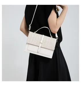 Detailed view of women's beige crossbody bag with woven straw flap on a model