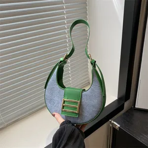 Bolso de media luna en contraste verde y gris con hebilla metálica y luz natural