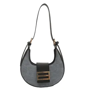 Bolso hobo retro de fieltro gris y cuero negro con hebilla dorada sobre un fondo blanco
