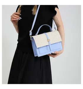 Detail of light blue and beige woven crossbody bag with golden round clasp and adjustable strap