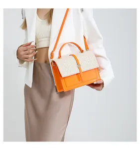 Detail of orange leather shoulder bag with white straw woven flap and golden buckle