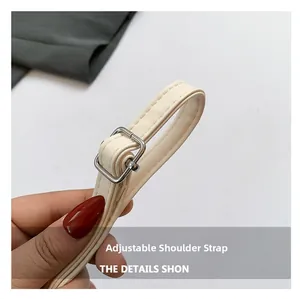 Detail of adjustable shoulder strap with silver metal buckle on cream faux leather bag