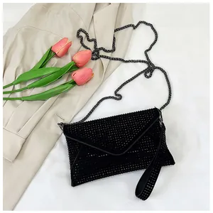 Detail of black rhinestone envelope bag with metallic chain and sparkling wrist strap
