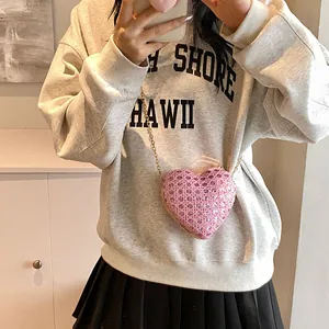 Détail du sac coeur rose orné de strass avec bandoulière chaîne dorée porté par mannequin