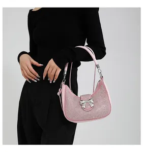 Close-up of pink rhinestone underarm bag with silver metal bow and leather strap