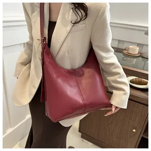 Detail of burgundy leather hobo bag showing sewing line and metal ring strap connection
