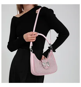 Close-up of pink rhinestone handbag featuring a silver metal bow accent and leather strap