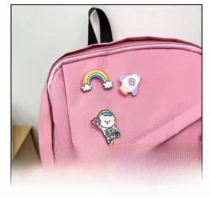 Gros plan d'un sac à dos en toile rose avec des épingles émaillées arc-en-ciel et astronaute