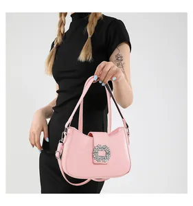 Detail of pink shoulder bag with large floral rhinestone buckle on sleek synthetic leather