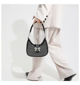 Close-up of black rhinestone underarm bag with silver metal bow and crescent shape