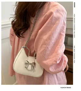 Détail d'un sac à bandoulière blanc demi-lune avec nœud en métal argenté et chaîne