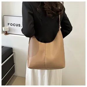Detail of khaki leather tote bag on model showing large capacity and textured stitching