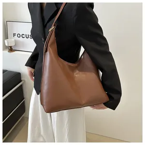 Detail view of brown leather hobo bag with vertical stitching and gold ring hardware