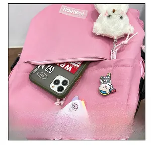 Gros plan d'un sac à dos rose en toile avec poche zippée externe et pendentif ours