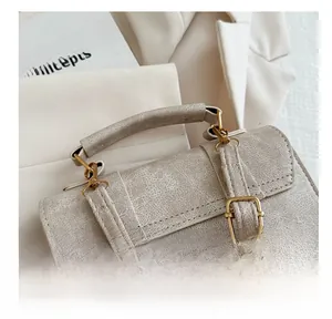Detailed close-up of cream white faux leather handbag with crackle texture and gold buckles
