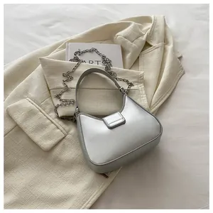 Détail du sac sous l'aisselle argenté en croissant avec finition et chaîne décorative chic