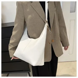 Detailed shot of white tote bag with wide shoulder strap and gold-tone hardware