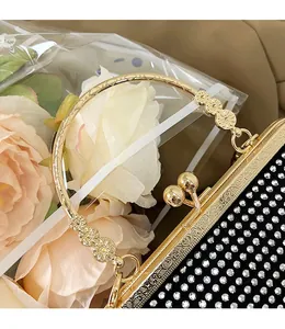 Detailed shot of sparkling rhinestones and an ornate gold metal handle on a black clutch