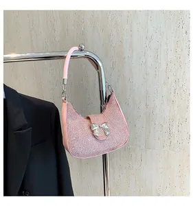 Close-up of pink rhinestone shoulder bag with silver metallic bow detail and strap