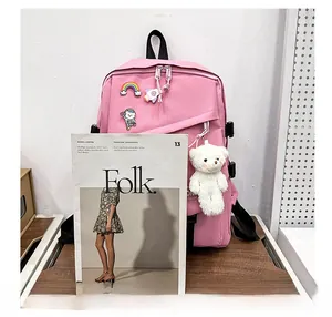 Détail du sac à dos en nylon rose avec badges de dessin animé et pendentif ours en peluche