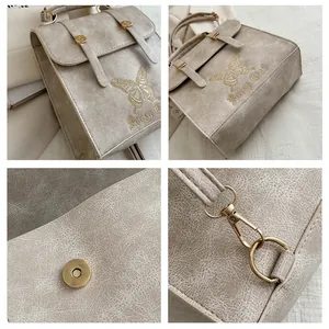 Detailed view of beige faux leather backpack showing butterfly embroidery and gold hardware
