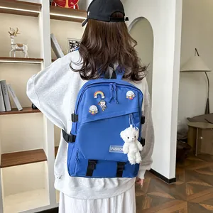 Détail d'un sac à dos d'école en nylon bleu avec épinglettes astronaute et ours peluche
