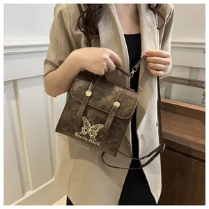 Detail of dark brown vintage faux leather bag featuring golden butterfly embroidery