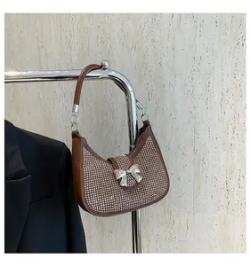 Detail of a brown rhinestone hobo bag featuring a silver bow accent and leather strap