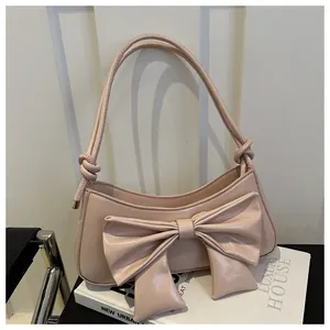 Detalle del gran lazo decorativo y la textura de cocodrilo en este bolso rosa al hombro