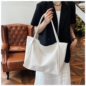 Detail of white woven tote bag texture and long handles on model in cozy interior