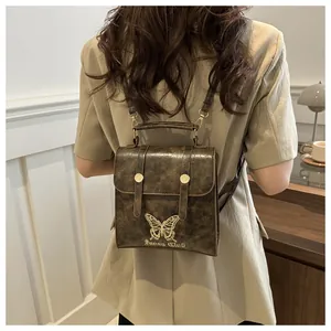Detail of vintage brown PU leather backpack with gold butterfly embroidery and metal buckles