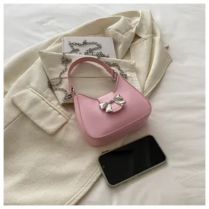 Détail du sac à main demi-lune rose avec nœud argenté et bandoulière en chaîne fine