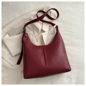 Close-up of wine red leather hobo bag with vertical stitching and wide shoulder strap