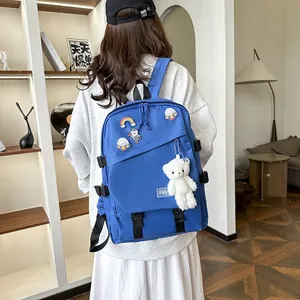 Détail d'un sac à dos d'école bleu avec des badges de dessin animé et un ours en peluche