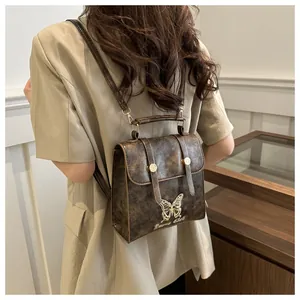 Detail of vintage brown PU leather backpack with butterfly ornament and Fairy Club text