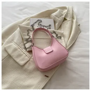 Détail d'un sac à main rose en demi-lune avec chaîne argentée sur une veste