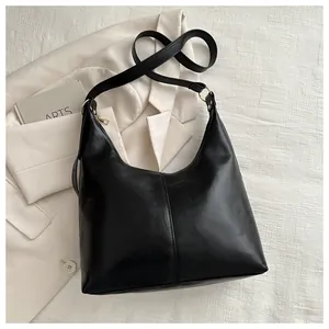 Detail of a black hobo bag with sleek leather texture, gold hardware, and decorative stitching