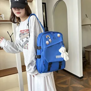 Détail d'un sac à dos bleu avec badges astronaute et porte-clé ours en peluche blanc