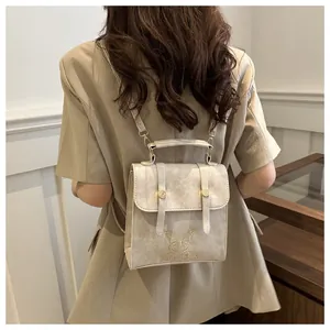 Detail showing beige leather backpack with butterfly embroidery and buckle flap design
