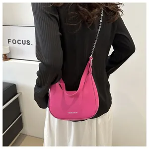 Detail van rozerode maanvormige tas met lychee-textuur en zilveren ketting
