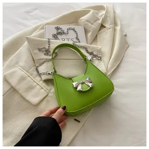 Gros plan du sac sous le bras vert vif avec boucle noeud argentée et détail de chaîne